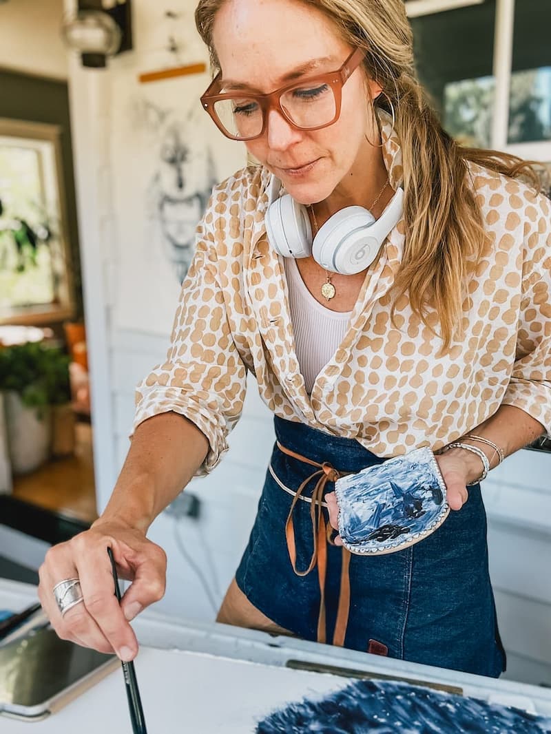 Shayna painting in her porch studio wearing a yellow shirt